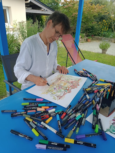 Pierre Quentel dessine à une table dans le jardin